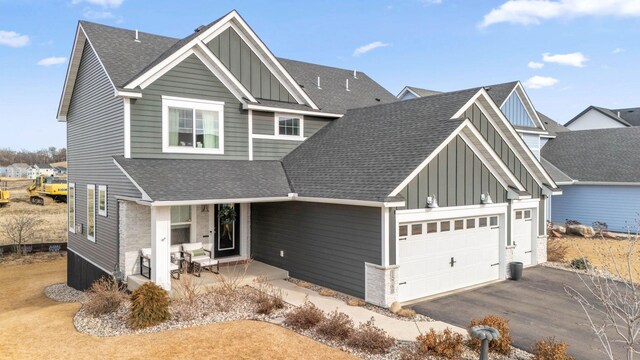 view of front facade with board and batten siding, a shingled roof, driveway, and a garage