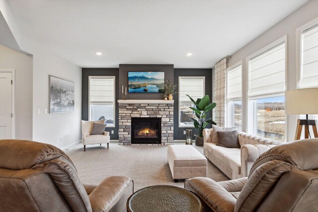 living room featuring recessed lighting, baseboards, carpet, and a stone fireplace