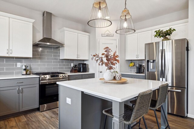 kitchen with stainless steel appliances, tasteful backsplash, dark wood finished floors, and wall chimney range hood