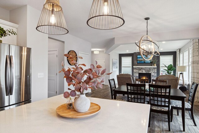 dining area with a stone fireplace, an inviting chandelier, and wood finished floors
