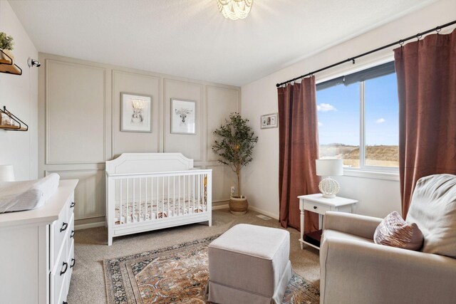 bedroom with a nursery area, light colored carpet, and baseboards