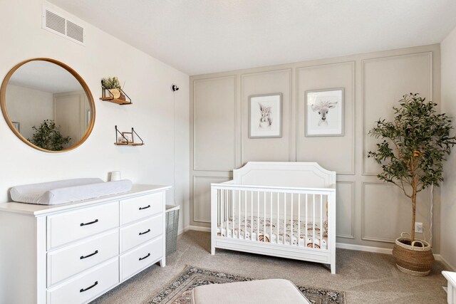 bedroom with a decorative wall, a nursery area, light colored carpet, and visible vents
