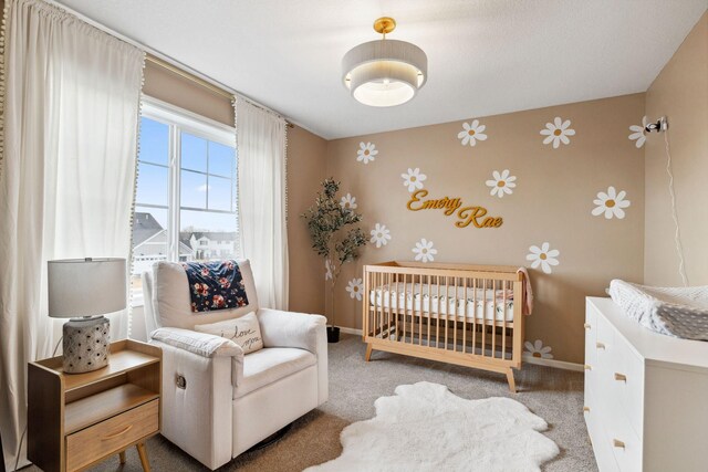 bedroom with wallpapered walls, a crib, carpet, and baseboards