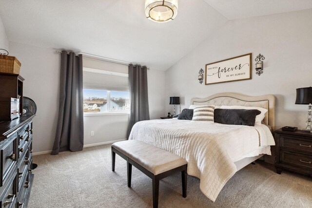 bedroom featuring light colored carpet, baseboards, and lofted ceiling