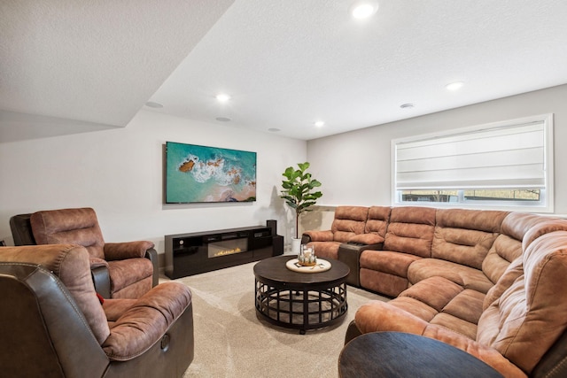 living area featuring a glass covered fireplace, recessed lighting, a textured ceiling, and carpet