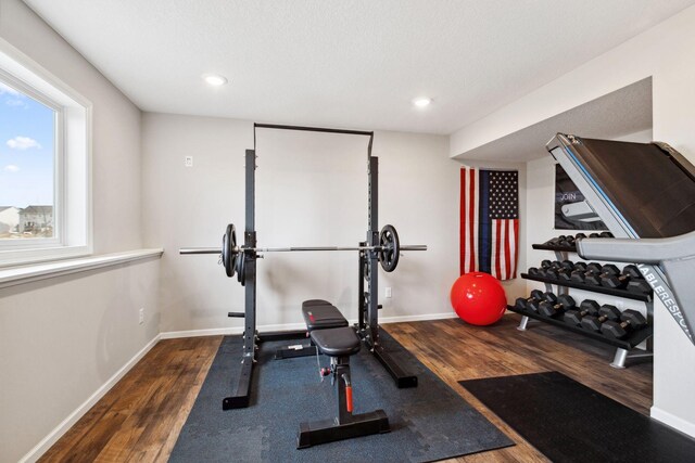 exercise room with baseboards and wood finished floors
