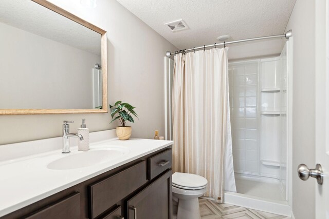 bathroom with visible vents, toilet, a stall shower, a textured ceiling, and vanity
