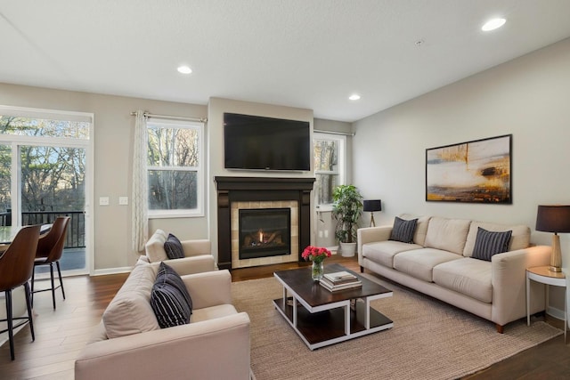 living room featuring wood finished floors, a fireplace, baseboards, and recessed lighting