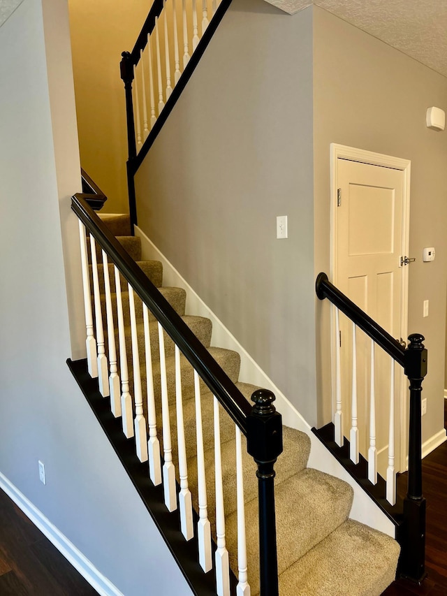 staircase featuring wood finished floors and baseboards