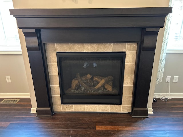 room details featuring baseboards, wood finished floors, visible vents, and a fireplace