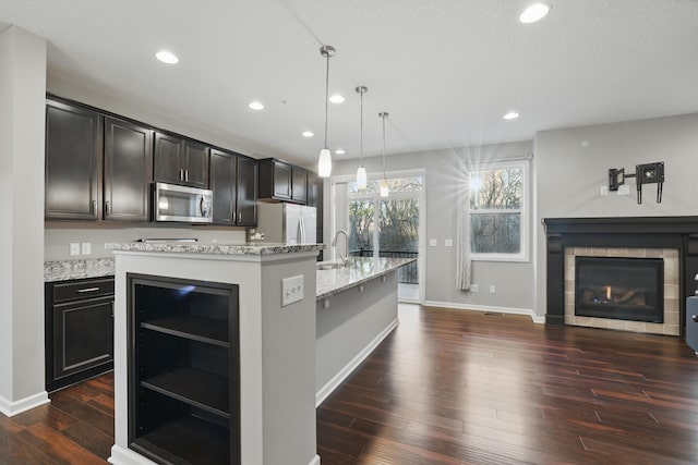 kitchen with dark wood-type flooring, a center island with sink, stainless steel appliances, and recessed lighting