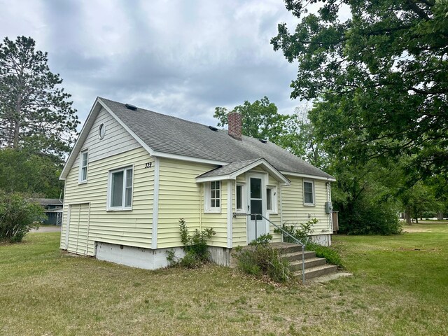 329 Main St NW, Menahga, MN 56464 - view of front of property with a chimney, a front yard, and a shingled roof