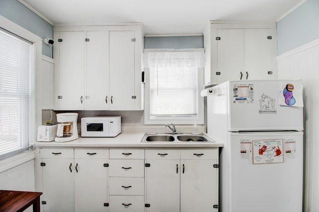 329 Main St NW, Menahga, MN 56464 - kitchen with white appliances, a sink, light countertops, white cabinetry, and crown molding