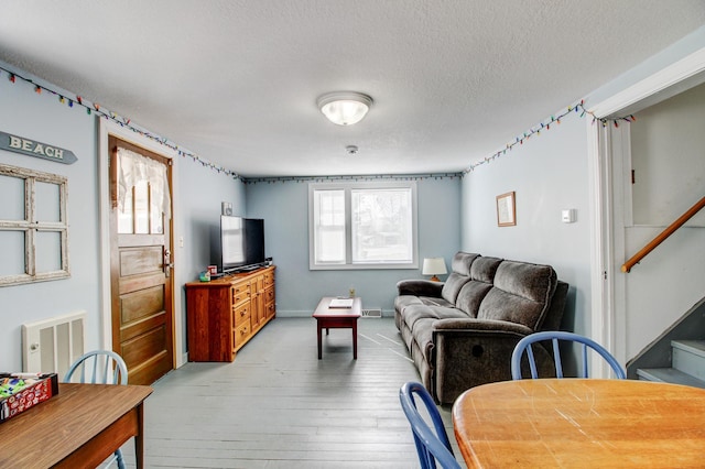 329 Main St NW, Menahga, MN 56464 - living room featuring light wood-type flooring, stairs, and a textured ceiling