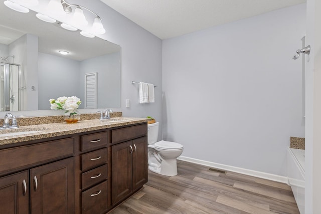 8949 Village Loop, Chanhassen, MN 55317 - bathroom featuring toilet, wood finished floors, a stall shower, double vanity, and baseboards