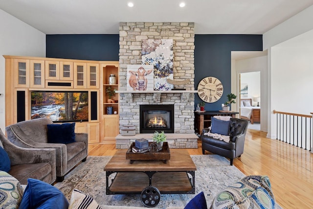 living room with light wood-style floors, recessed lighting, and a stone fireplace