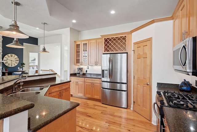 kitchen with glass insert cabinets, a sink, stainless steel appliances, light brown cabinetry, and light wood-type flooring