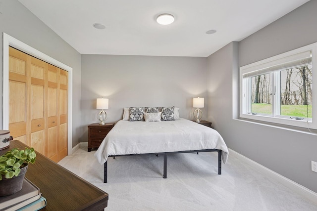 bedroom with a closet, light carpet, and baseboards