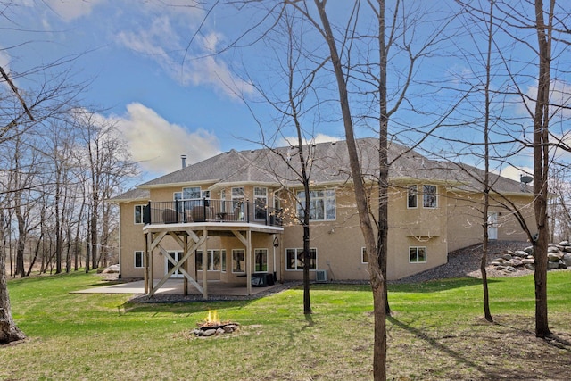 back of property with a patio, a lawn, a fire pit, and stucco siding