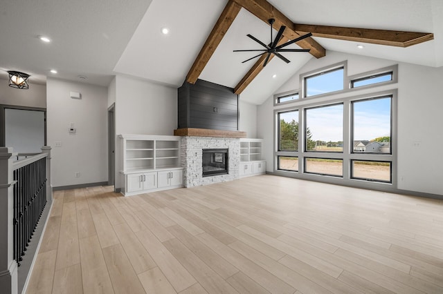 unfurnished living room with baseboards, beamed ceiling, light wood finished floors, and a stone fireplace