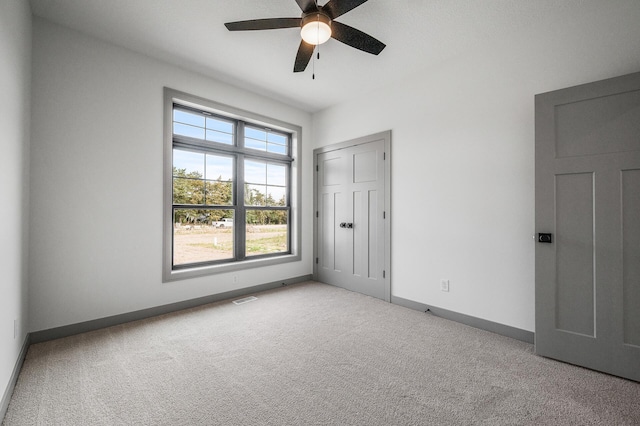 unfurnished bedroom featuring carpet, a ceiling fan, baseboards, visible vents, and a closet