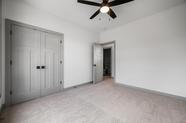 unfurnished bedroom featuring baseboards, a ceiling fan, a closet, and light carpet