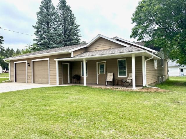 222 Dogwood Ave NW, Menahga, MN 56464 - view of front of home featuring a front lawn, a garage, concrete driveway, and covered porch