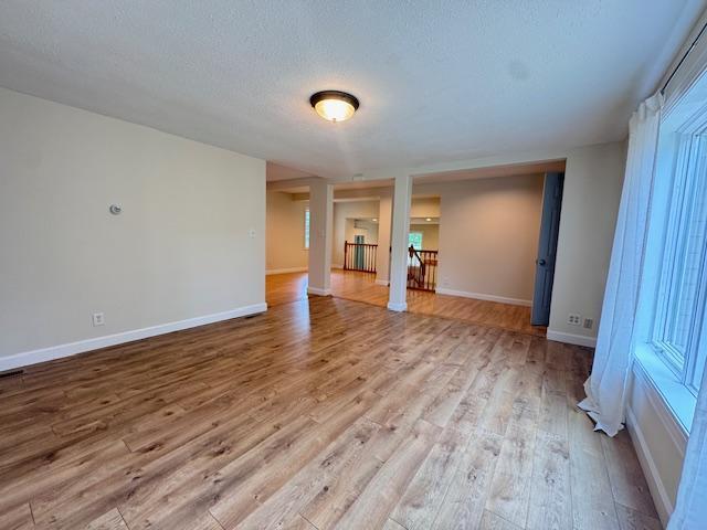 222 Dogwood Ave NW, Menahga, MN 56464 - unfurnished living room with wood finished floors, a textured ceiling, and healthy amount of natural light