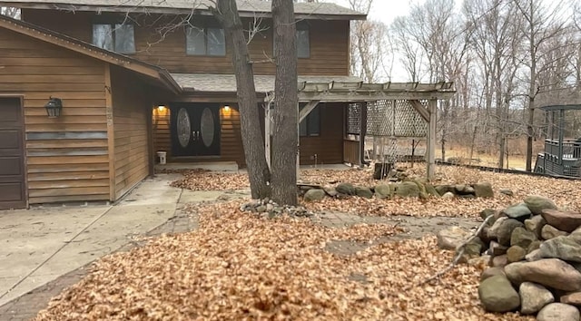 property entrance featuring a pergola and roof with shingles