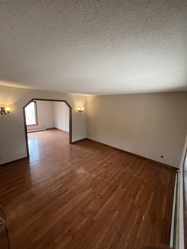 bonus room featuring a baseboard heating unit, wood finished floors, and a textured ceiling