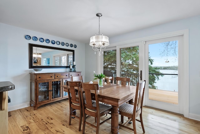 dining space featuring an inviting chandelier, light wood finished floors, and baseboards
