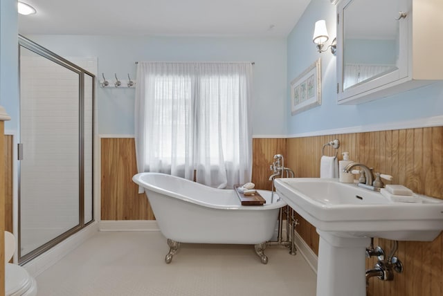 full bath with wood walls, wainscoting, a freestanding tub, and a shower stall