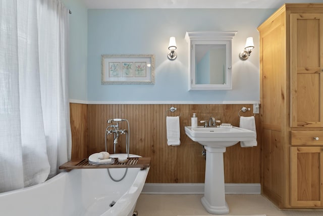 bathroom with wooden walls, wainscoting, and a soaking tub