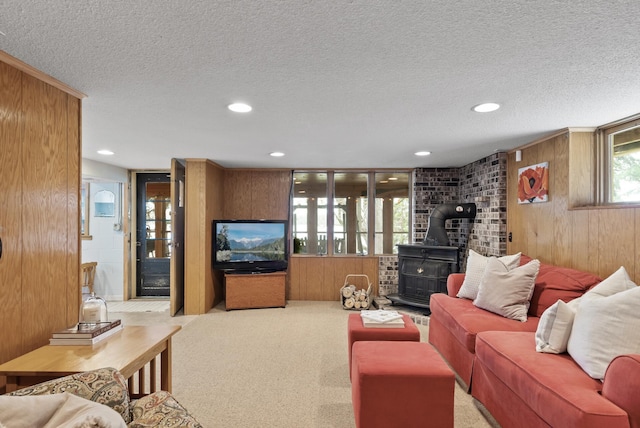 living room with carpet floors, a wood stove, wood walls, recessed lighting, and a textured ceiling