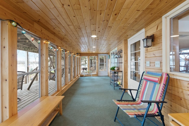 unfurnished sunroom with carpet flooring, wood ceiling, and wood walls
