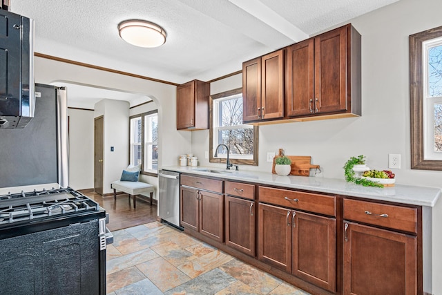 6524 Minnetonka Blvd, Saint Louis Park, MN 55426 - kitchen featuring a sink, appliances with stainless steel finishes, light countertops, arched walkways, and a textured ceiling