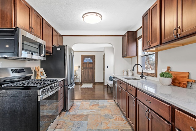 6524 Minnetonka Blvd, Saint Louis Park, MN 55426 - kitchen featuring appliances with stainless steel finishes, arched walkways, a sink, light stone finish flooring, and a textured ceiling