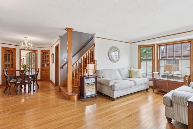 living area featuring an inviting chandelier, stairs, light wood-type flooring, and ornamental molding