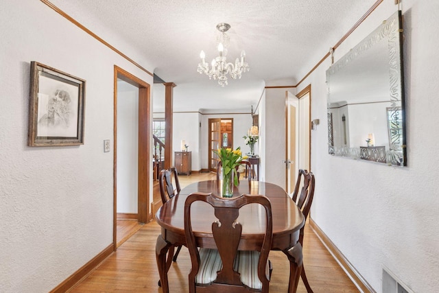 dining space featuring a notable chandelier, light wood-style floors, baseboards, and a textured wall