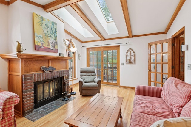 living room featuring baseboards, a brick fireplace, crown molding, wood finished floors, and vaulted ceiling with skylight