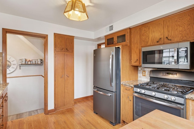 kitchen with brown cabinets, light wood-style floors, visible vents, and appliances with stainless steel finishes