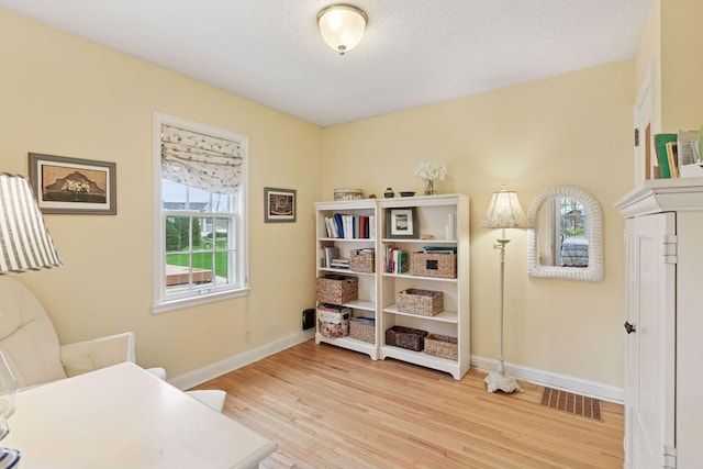 living area with wood finished floors, visible vents, and baseboards
