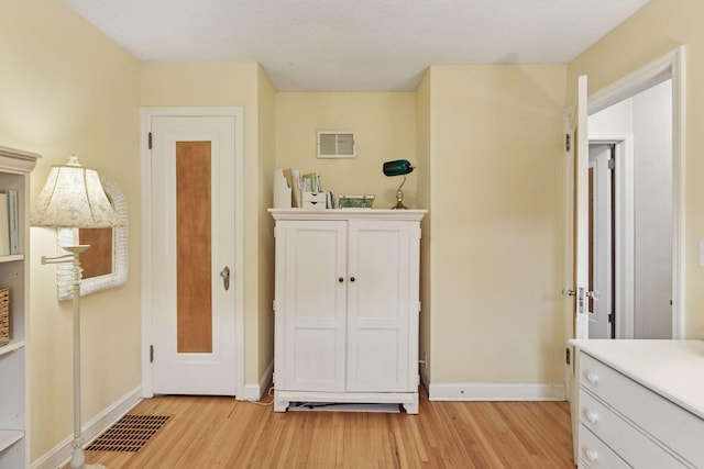 bedroom with light wood-type flooring, visible vents, and baseboards