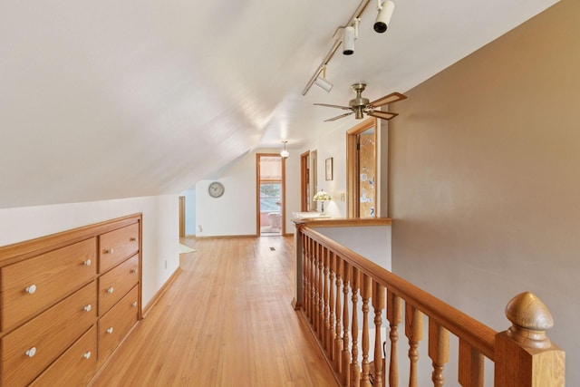hallway featuring an upstairs landing, rail lighting, light wood-type flooring, baseboards, and lofted ceiling