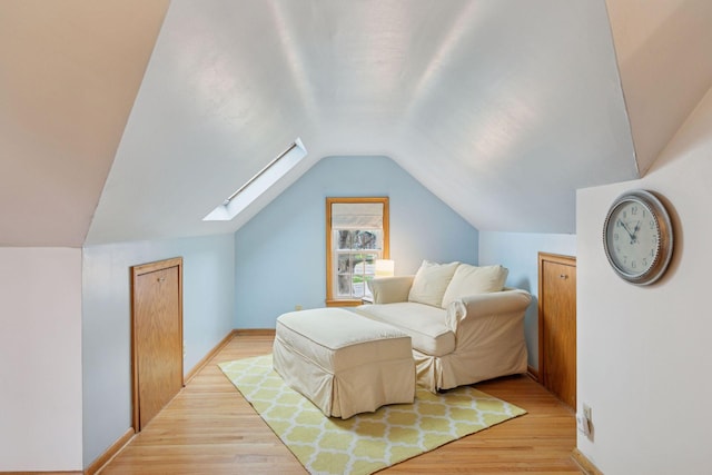bedroom featuring baseboards, lofted ceiling with skylight, and light wood finished floors