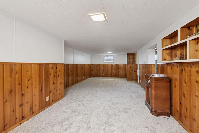 basement featuring wood walls, carpet floors, and a wainscoted wall