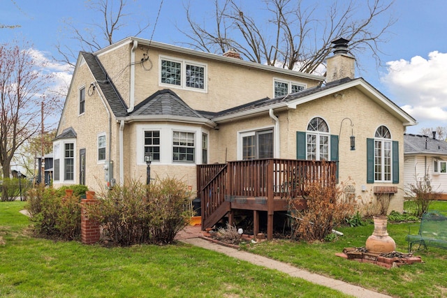rear view of property with stucco siding, a chimney, a lawn, and a deck