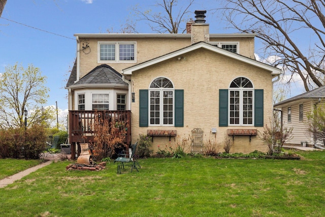 back of house with a chimney, a wooden deck, stucco siding, and a lawn