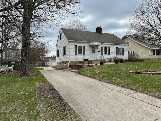view of front of house featuring roof with shingles, a chimney, concrete driveway, and a front yard