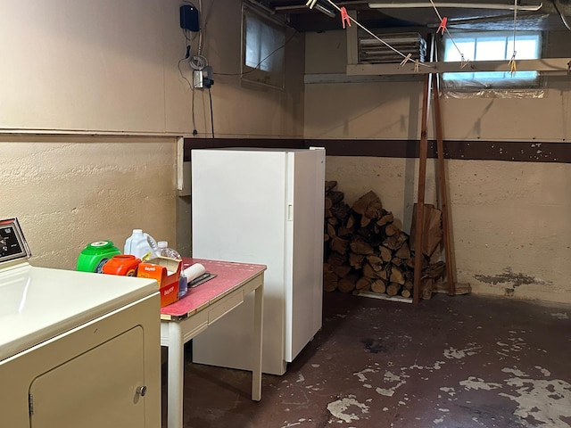 unfinished basement featuring freestanding refrigerator and washer / dryer